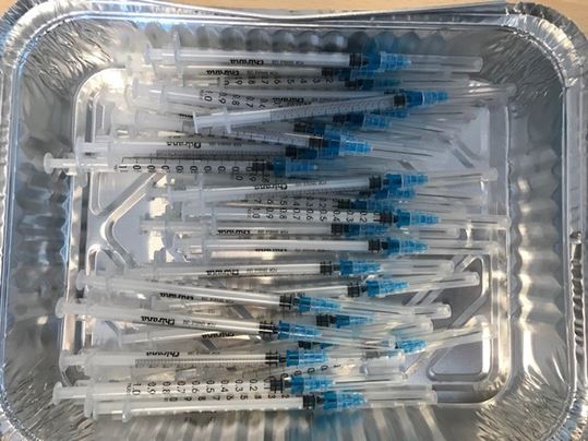 Foliebakke fyldt med tomme vaccinationssprøjter