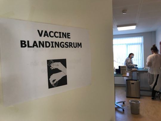 Skilt der hænger på væggen med teksten Vaccine blandingsrum